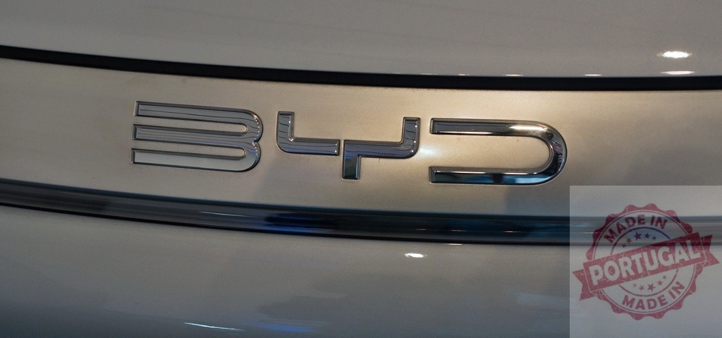 BYD car badge on electric vehicle trunk | BYD chrome emblem on a white electric car, representing sustainable transport technology - Realized with Pictrs.com