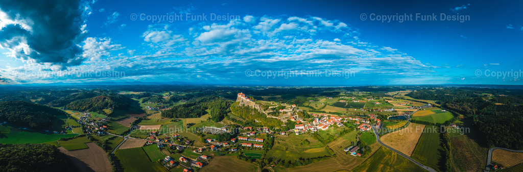 Drohnenpanorama der Riegersburg – Steiermark, Österreich | Die Riegersburg thront majestätisch auf ihrem markanten Felsen und blickt weit über das steirische Hügelland. Aus der Drohnenperspektive wirkt die Anlage besonders eindrucksvoll, eingerahmt von Feldern, Wäldern und einem dramatischen Himmel.