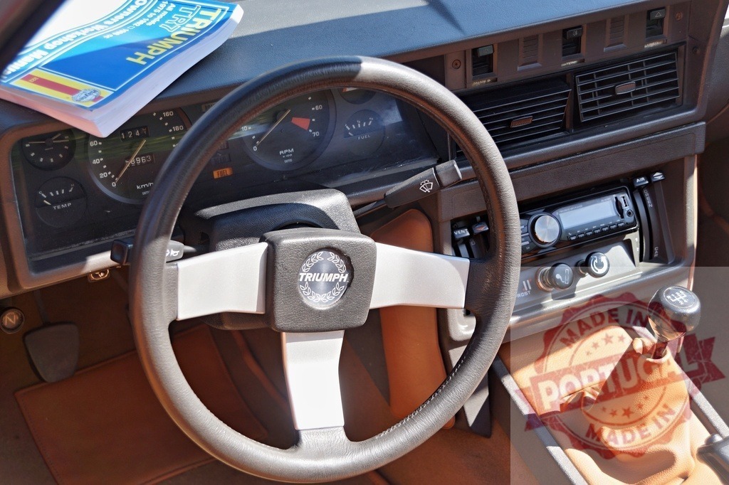 Triumph TR7 dashboard with manual and classic steering wheel | Triumph TR7 interior featuring dashboard, steering wheel, gearshift and repair manual - Realized with Pictrs.com