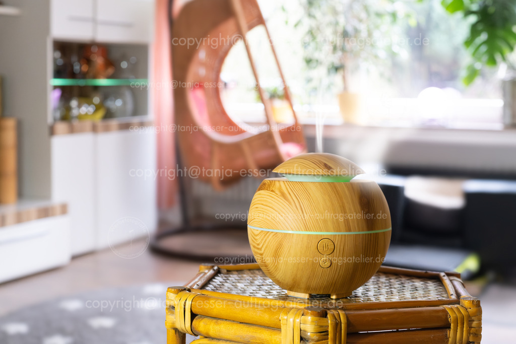 Nahaufnahme zeigt einen hölzernen Aroma Diffuser in einem Wohnzimmer. | Ein Diffuser verteilt aromatisiertes Wasser als Dampf im Wohnzimmer. Unscharfer Hintergrund mit Copy Space. 