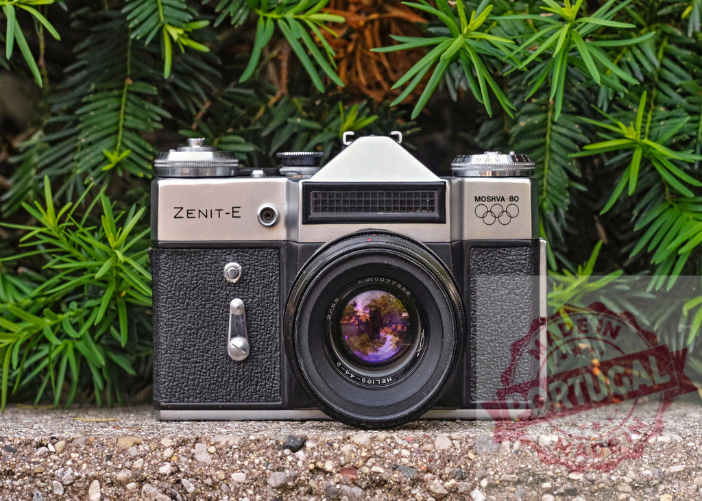 Zenit-E vintage film camera from MOSKVA 80 Olympics | Zenit-E vintage SLR film camera with Helios-44-2 lens sitting on stone in front of green foliage - Realisiert mit Pictrs.com
