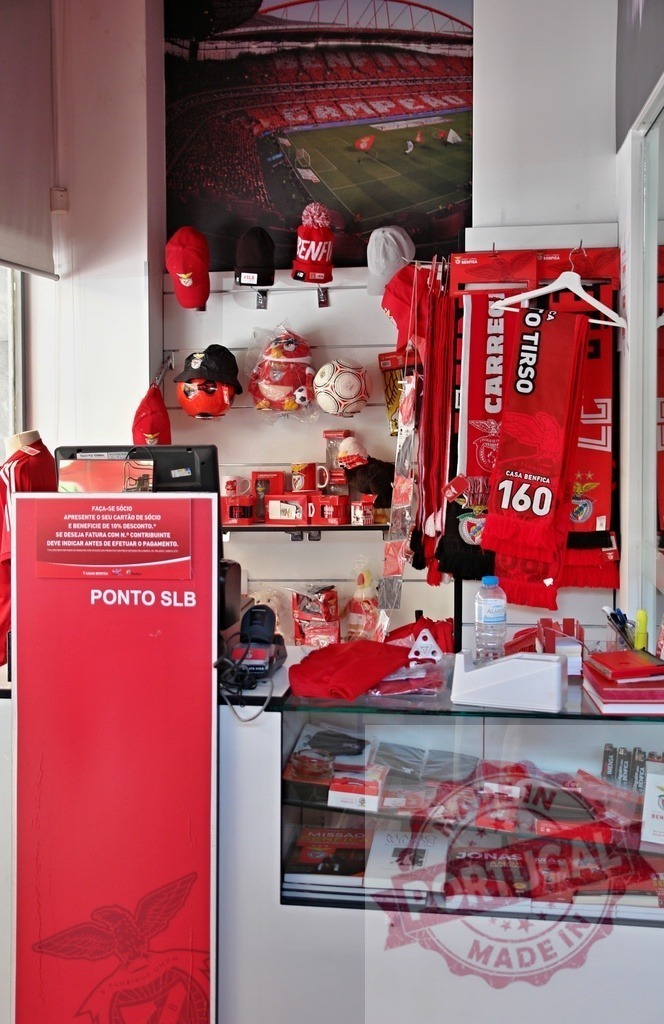 S.L. Benfica retail shop displaying soccer merchandise | S.L. Benfica shop interior showcasing various red fan gear and stadium poster - Realisiert mit Pictrs.com