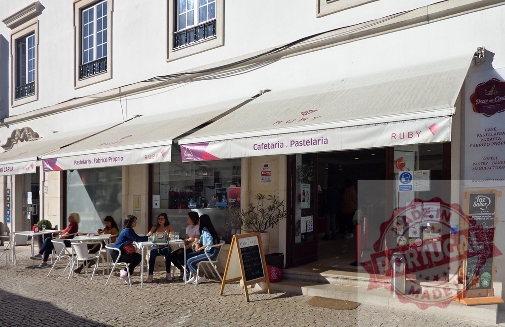 People enjoying a sunny day at a cafe terrace in Portugal | People relaxing at an outdoor cafe on a cobblestone street during a sunny day - Realized with Pictrs.com
