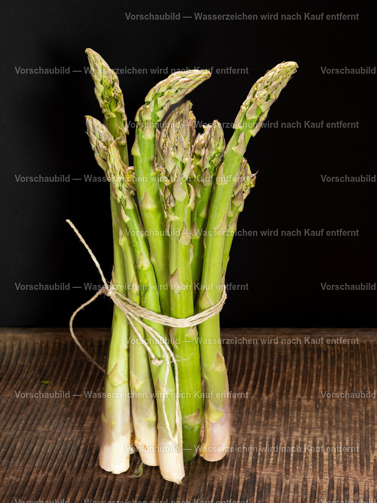 ein Bund frischer, grüner Spargel stehend auf alten Holzbrett | ein Bund frischer, grüner Spargel stehend auf alten Holzbrett - Realisiert mit Pictrs.com