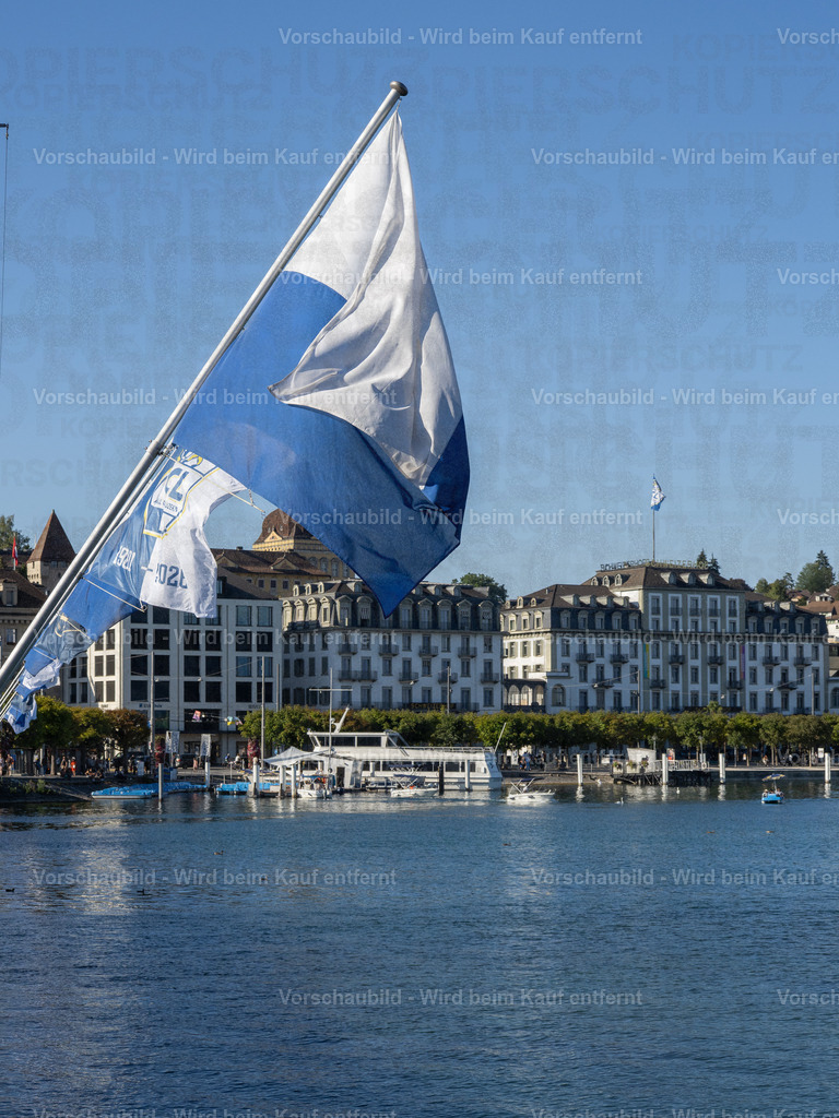 125 Jahre FCL – Luzern in Blau-Weiss | Die blau-weissen Fahnen wehen an der Seebrücke im Wind und zelebrieren das 125-Jahre-Jubiläum des FC Luzern. Dahinter erstreckt sich die Kulisse der Luzerner Seepromenade mit dem traditionsreichen Hotel Schweizerhof. - Realisiert mit Pictrs.com