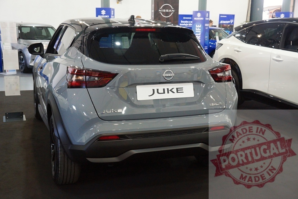 Nissan Juke crossover SUV parked at car dealership display | Rear view of a gray Nissan Juke crossover SUV on display indoors - Realized with Pictrs.com