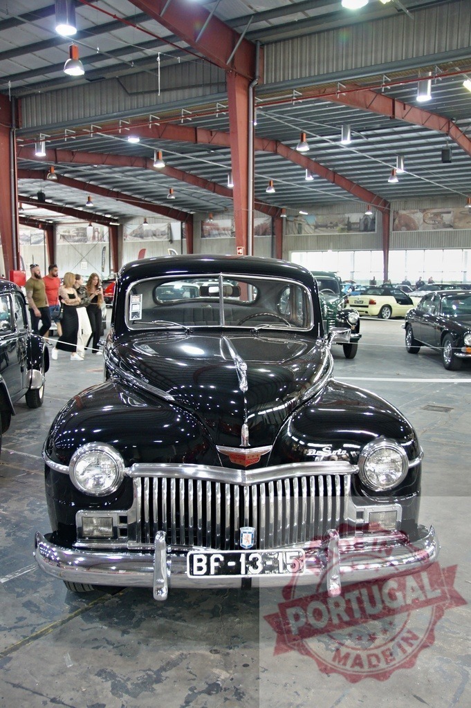 Restored DeSoto Deluxe four-door sedan posing in a classic car exhibition | Shiny black DeSoto Deluxe posing in a classic car exhibition with visitors walking in the background - Realisiert mit Pictrs.com
