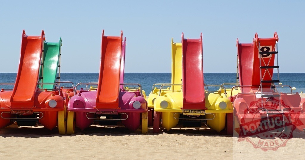 Colorful pedal boats with slides parked on beach | Colorful pedal boats with slides waiting on a sandy beach by the clear blue sea - Realisiert mit Pictrs.com