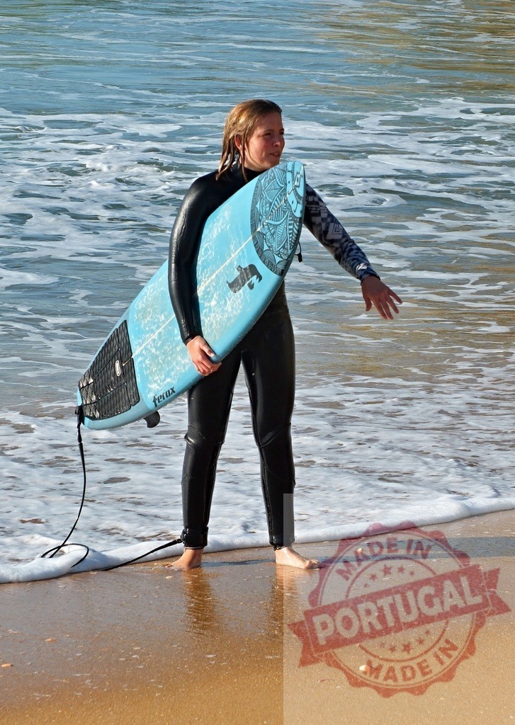 Woman surfer holding board standing on beach | Woman in wetsuit carrying a surfboard walking from ocean waves onto the sand - Realisiert mit Pictrs.com