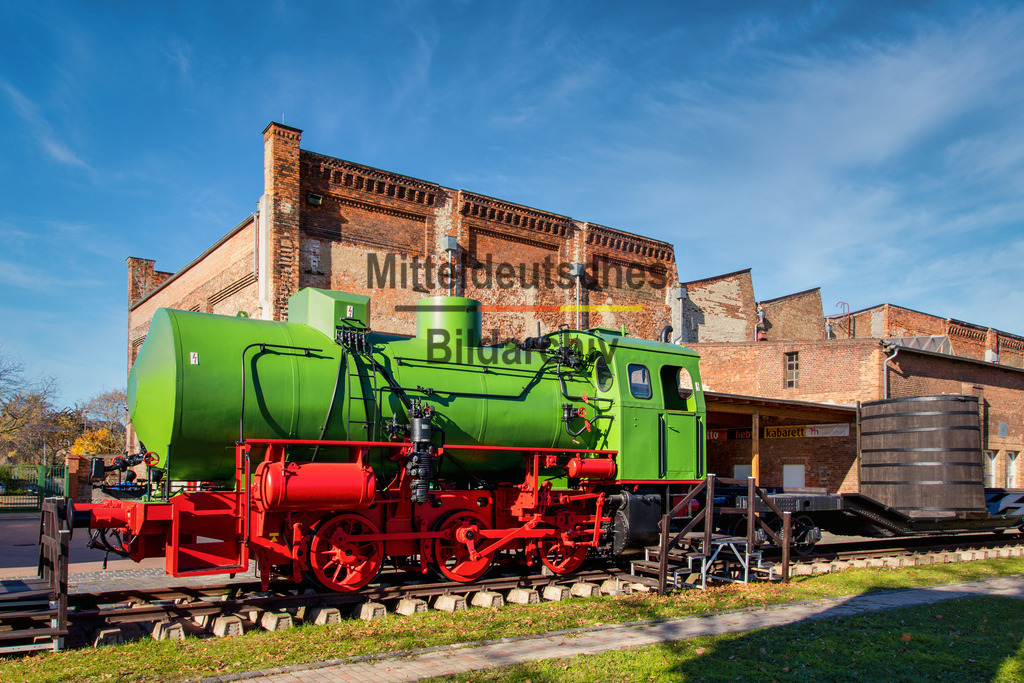 Magdeburg Technikmuseum Dampfspeicherlokomotive-6622 | Das Foto zeigt das markante grüne Schiff im Wissenschaftshafen Magdeburg aus einer bodennahen Perspektive. Der technische Arbeits- und Funktionscharakter des Schiffes wird durch den robusten Stahlrumpf, die großzügigen Arbeitsdecks und die funktionale Ausrüstung deutlich. Die niedrige Kameraposition hebt die markante Silhouette hervor und vermittelt einen eindrucksvollen Eindruck der Konstruktion.Arbeitsschiffe dieser Bauart werden für vielfältige Aufgaben auf den Binnenwasserstraßen eingesetzt. Je nach Ausstattung übernehmen sie Unterhaltungsarbeiten an Hafenanlagen und Wasserstraßen, den Transport von Material und Geräten oder dienen als Arbeitsplattform für Wartungs- und Vermessungsarbeiten. Die vollständig geschweißte Stahlkonstruktion ist auf hohe Belastungen ausgelegt und bietet durch ihre kompakte Bauweise eine hohe Manövrierfähigkeit auch in engen Hafenbereichen.Die Aufnahme dokumentiert ein charakteristisches Beispiel moderner Binnenschiffstechnik im Wissenschaftshafen Magdeburg. Das Schiff steht stellvertretend für die technische Entwicklung der Arbeits- und Versorgungsschifffahrt und unterstreicht die enge Verbindung des Wissenschaftshafens mit der traditionsreichen Schifffahrts- und Wasserbautechnik der Landeshauptstadt. - Realisiert mit Pictrs.com