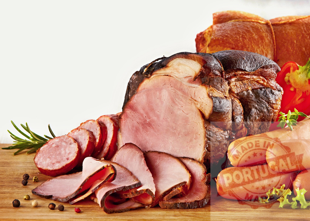 Smoked ham, sliced salami, sausages, and cold cuts display | Assortment of smoked ham, salami, and various deli meats arranged on a rustic cutting board - Realisiert mit Pictrs.com