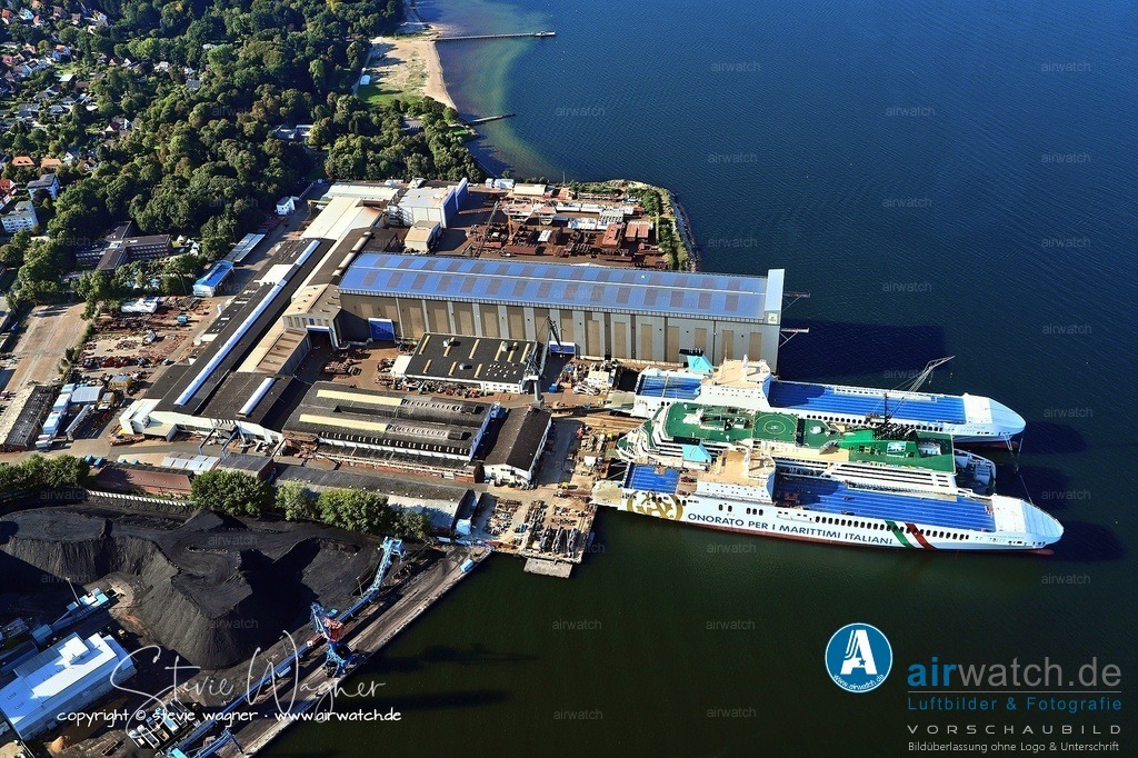 Luftbild Flensburger Schiffbau Gesellschaft - FSG | Während des Zeitraums von 1914 bis 1918, also im Ersten Weltkrieg, war die Flensburger Schiffbau-Gesellschaft (FSG) bereits ein etabliertes Schiffbauunternehmen. Die Werft wurde ursprünglich 1872 gegründet und hatte bis zum Beginn des Krieges eine lange Tradition im Bau von Handelsschiffen sowie gelegentlich auch von Kriegsunterstützungsschiffen.