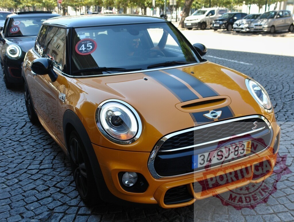 Stylish orange Mini Cooper S parked on cobblestone street | Modern orange Mini Cooper S with black stripes parked on a cobblestone street, showcasing its sporty design - Realized with Pictrs.com