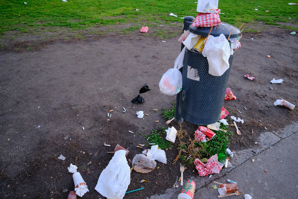 Abfalleimer und Rasen voll mit Müll | Wien, Austria - November 27, 2022: Abfalleimer und Rasen voll mit Müll. - Realisiert mit Pictrs.com