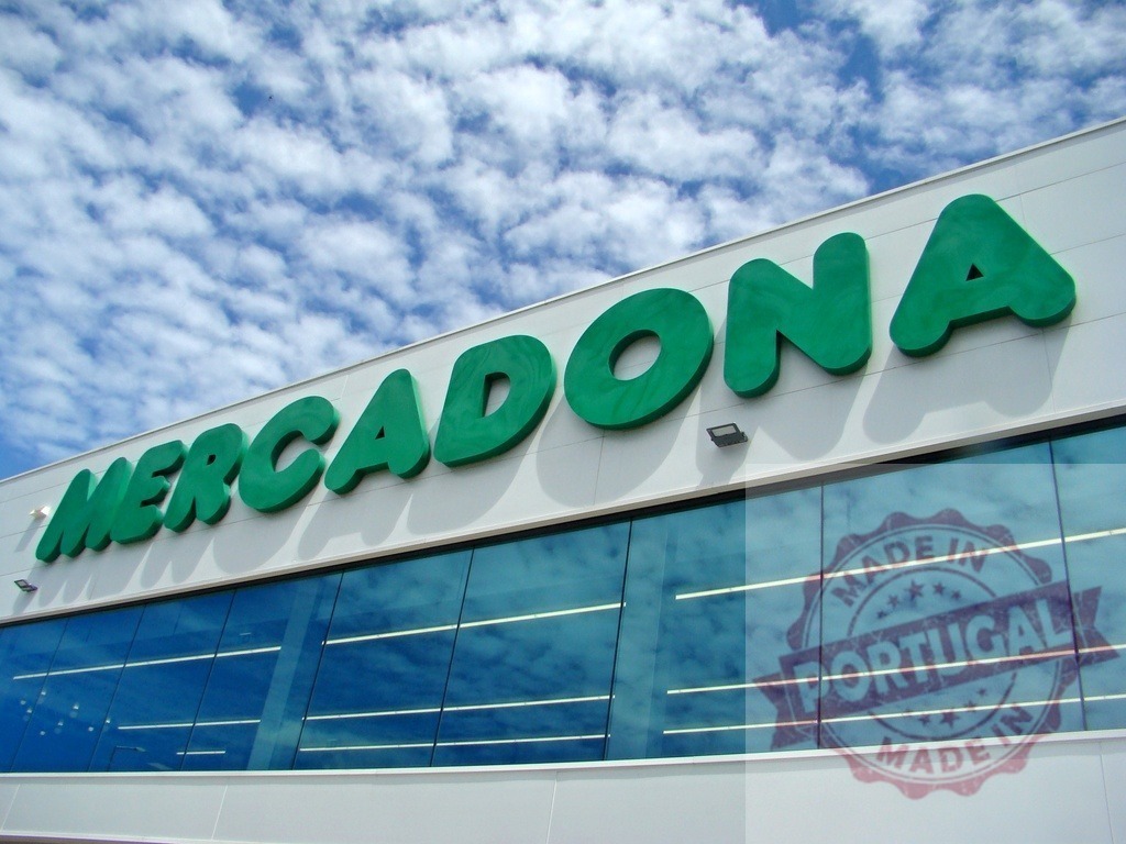 Mercadona supermarket sign on modern building facade | Mercadona grocery store facade with green logo and reflective windows under cloudy sky - Realized with Pictrs.com