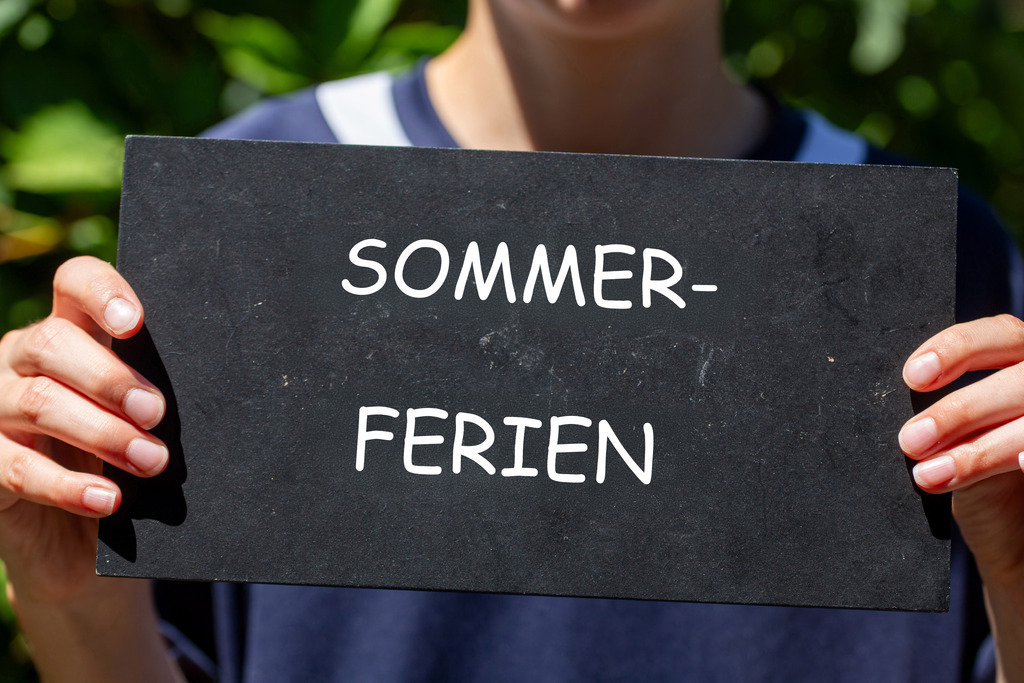 Symbolbild Sommerferien: Schüler hebt ein Schild mit der Aufschrift SOMMERFERIEN in der Hand | Symbolbild Sommerferien: Schüler hebt ein Schild mit der Aufschrift SOMMERFERIEN in der Hand - Realisiert mit Pictrs.com