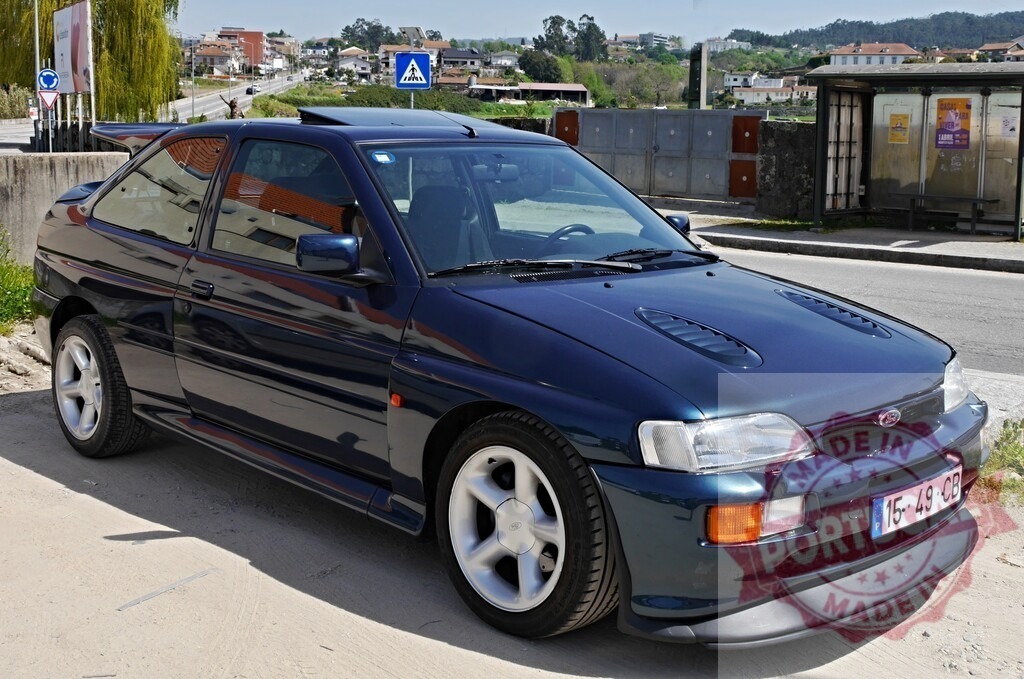 Ford Escort RS Cosworth sports car parked on street | Blue vintage Ford Escort RS Cosworth rally car parked during daytime outdoors - Realized with Pictrs.com