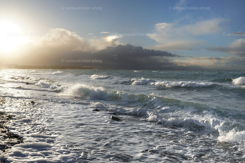 Windige Ostsee bei aufziehender Regenfront | Westwind bläst über die Ostsee und drückt die Schaumkronen an den Strand. Hinter der aufziehenden Regenfront zeigt sich für wenige Minuten eine grelle Nachmittagssonne im starken Gegenlicht.