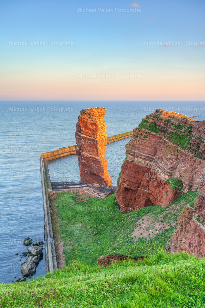 Lange Anna am Morgen | Blick zum Brandungspfeiler "Lange Anna" am Klippenende der Nordseeinsel Helgoland kurz nach Sonnenaufgang. Die Sonne bringt die Felsnadel zum Leuchten. - Realisiert mit Pictrs.com