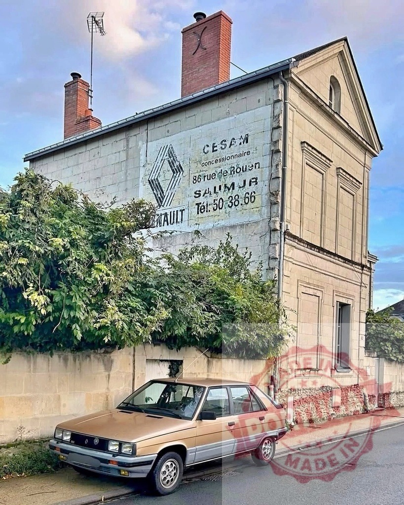 Renault 9 vintage car parked beside Saumur ghost sign | Renault 9 vintage car parked on a European street with an old Renault ghost sign on a building - Realized with Pictrs.com