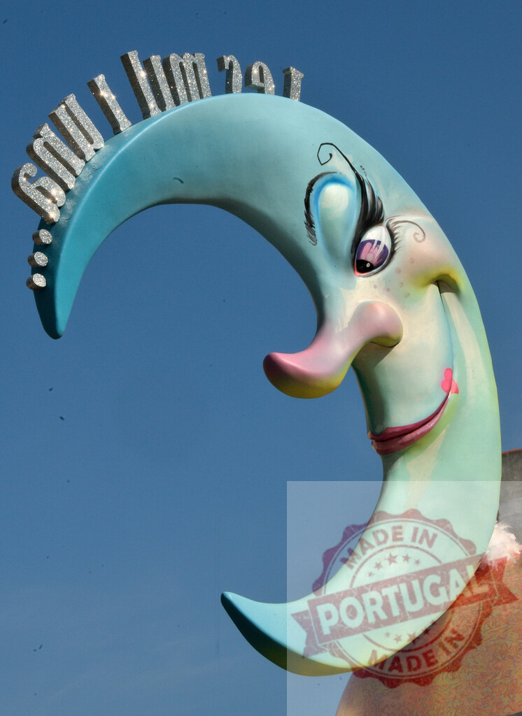 Carnival crescent moon character decorating festival against blue sky. Fallas Fiestas Communidad Valenciana | Decorative crescent moon character smiling with glitter lettering at a festival parade - Realized with Pictrs.com