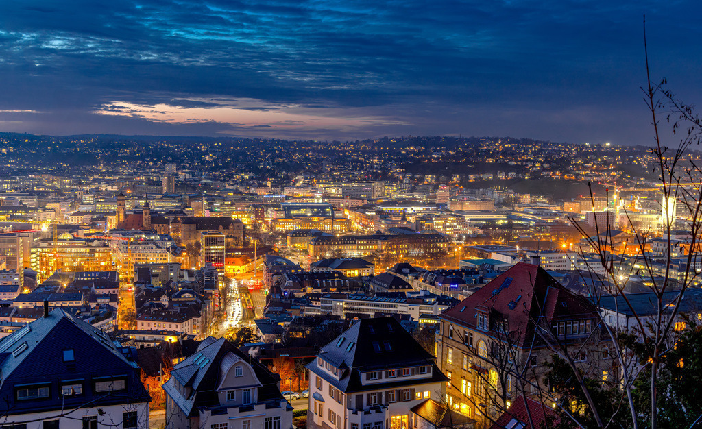 Nächtlicher Panoramablick auf die Innenstadt von Stuttgart,Schlossplatz | Das Bild zeigt einen nächtlichen Panoramablick auf die Innenstadt von Stuttgart. Die Aufnahme entstand von einem erhöhten Punkt aus, der einen weiten Blick über das beleuchtete Stadtzentrum in den Talkessel ermöglicht. Details zum BildStandort: Es handelt sich vermutlich um eine Aufnahme von der Uhlandshöhe oder einem ähnlichen Aussichtspunkt wie der Hasenbergsteige.Inhalt: Zu sehen ist der beleuchtete Stuttgarter Talkessel in der Abenddämmerung mit seinen charakteristischen Gebäuden und Straßenzügen. - Realisiert mit Pictrs.com