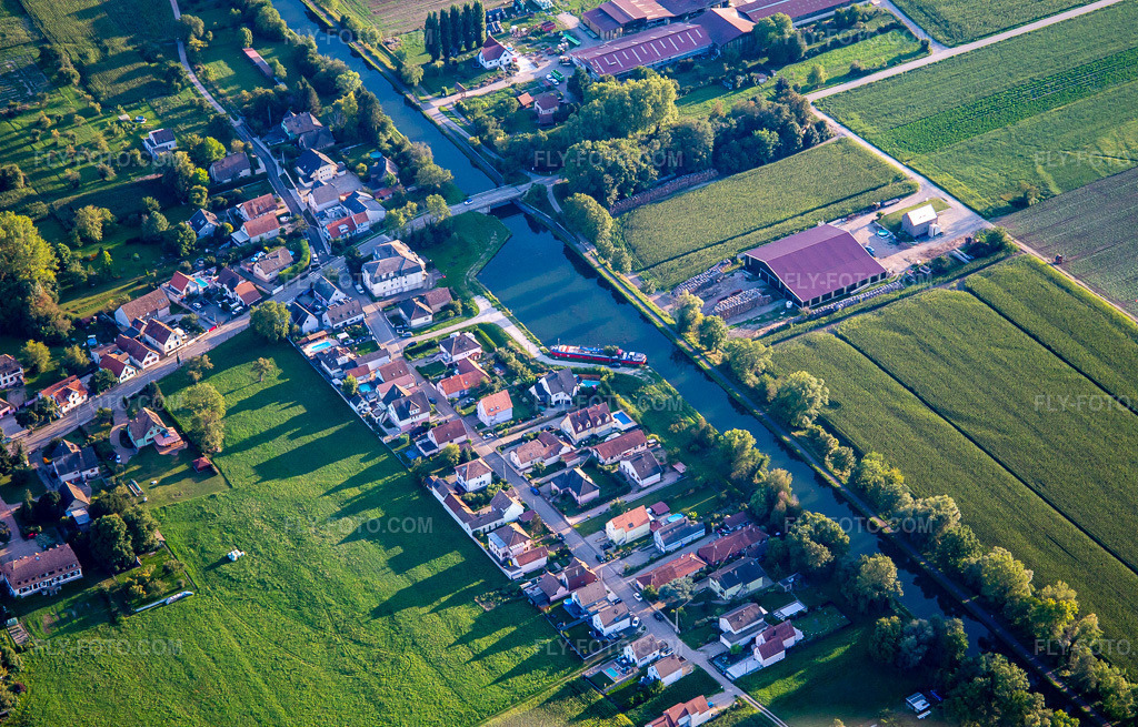 Aerial view: Rue du Canal on the Canal du Rhône au Rhin in Plobsheim in the state Bas-Rhin, France. – Photo: IMG_137879.jpg taken on 08/18/2023 by Werner Riehm/FLY-FOTO.com – Resolution of the original: 5223 x 3342 px