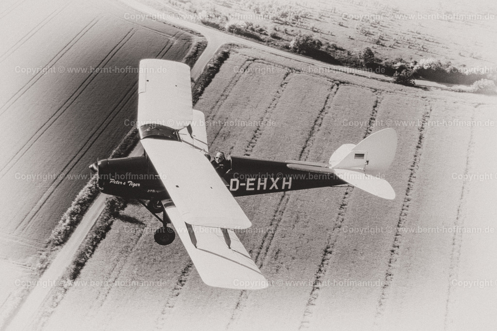 PLBDD_air2air_TigerMoth_08a_90x60 | Luftbild. Doppeldecker vom Typ TIGER MOTH über landwirtschaftlichen Flächen mit Feldern und Wäldern der Landschaft Angeln in Schleswig-Holstein. ___ Das Foto ist eine Reproduktion von einem Farbdia. Bildanmutung - schwarz-weiß Charakter mit Farbtonung. - Realisiert mit Pictrs.com