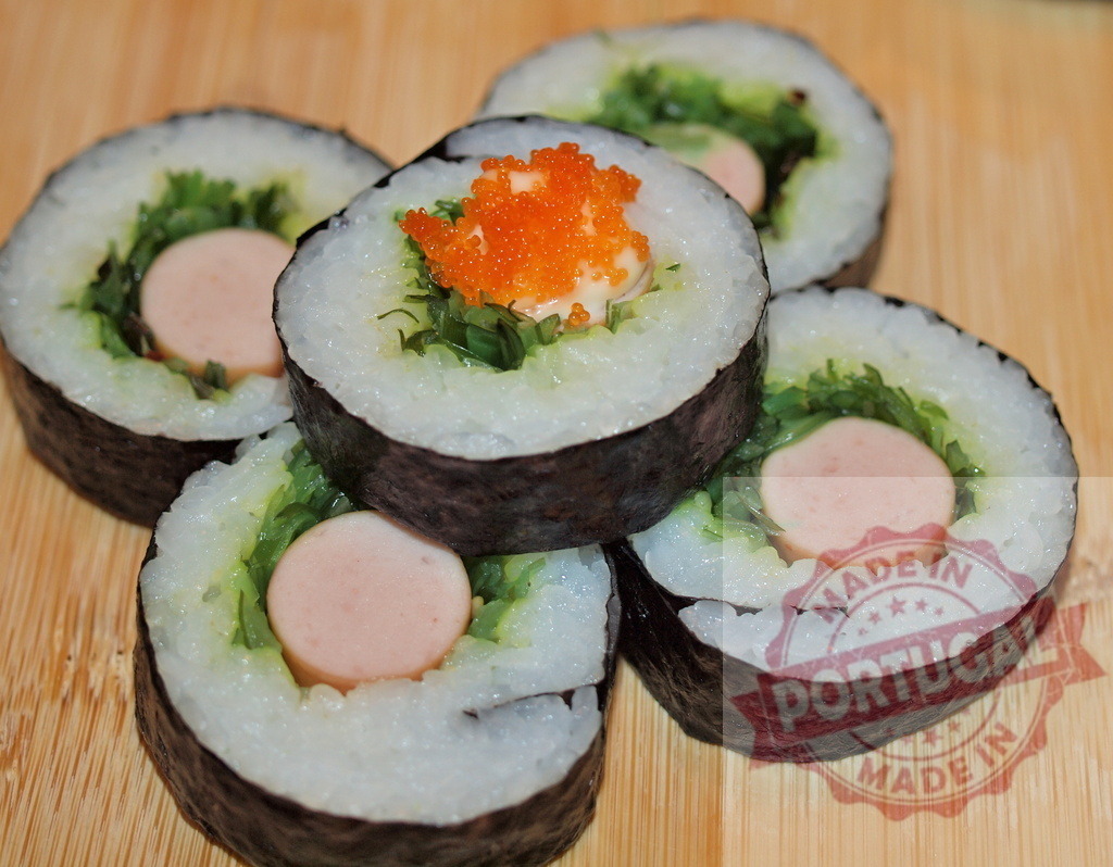 Creative sausage maki sushi rolls with tobiko | Fusion maki sushi rolls with sausage, rice, nori, and tobiko on a wooden board - Realisiert mit Pictrs.com