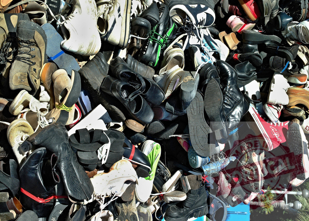 Large pile of used footwear on display outdoors | Many discarded shoes and boots creating a messy, cluttered heap - Realisiert mit Pictrs.com