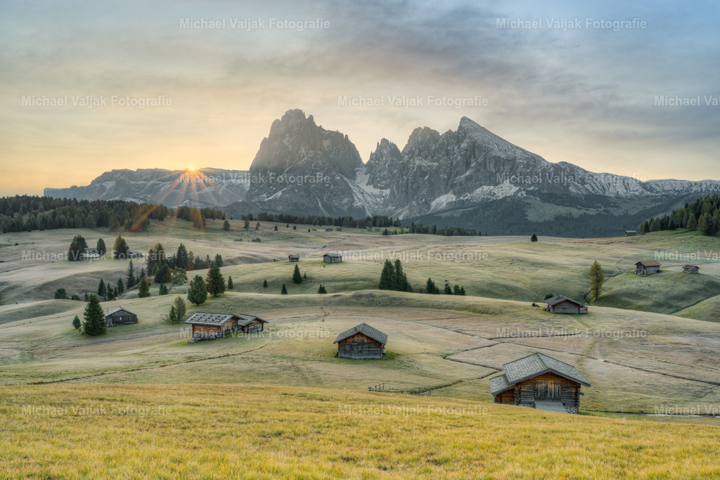 Sonnenaufgang auf der Seiser Alm im Herbst | Blick über die Almwiesen der Seiser Alm mit ihren vielen Hütten in Richtung Langkofel und Plattkofel bei einem Sonnenaufgang im Herbst. - Realisiert mit Pictrs.com