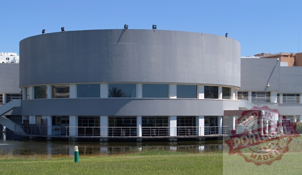Modern circular building with water and grass | Modern circular building with windows reflecting the sky, surrounded by water and green grass - Realisiert mit Pictrs.com