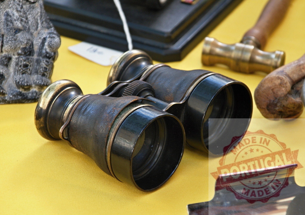 Vintage brass binoculars with leather on display | Antique opera binoculars and collectibles on a yellow cloth - Realized with Pictrs.com