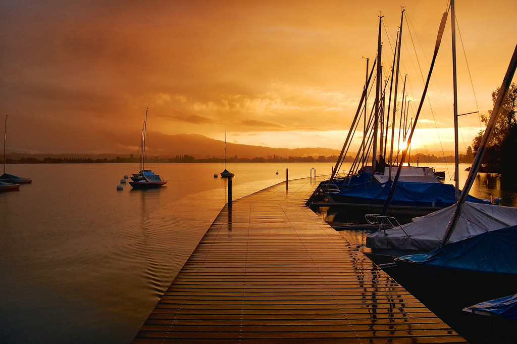 Regnerischer Sonnenuntergang | Eine besondere Stimmung entsteht bei einem Sonnenuntergang während es gleichzeitig regnet. Hier beim Hafen in Hilterfingen am Thunersee. 
-----------------------------------------------
A special atmosphere arises at a sunset while it is raining at the same time. Here at the port in Hilterfingen on Lake Thun.
-----------------------------------------------
Dieser Druck ist in einer limitierten Auflage von 10 Exemplaren erhältlich. 
This print is available in a limited edition of 10 copies. 
http://art.hess.photography/8-39-regnerischer-sonnenuntergang.html - Realisiert mit Pictrs.com