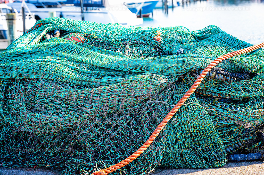 Stapel Fischernetze | Ein Stapel Fischernetze liegen am Kai im Hafen. - Realisiert mit Pictrs.com