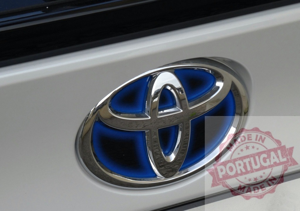 Toyota hybrid logo on modern electric vehicle | Toyota hybrid car emblem displaying blue and chrome details on vehicle body - Realized with Pictrs.com