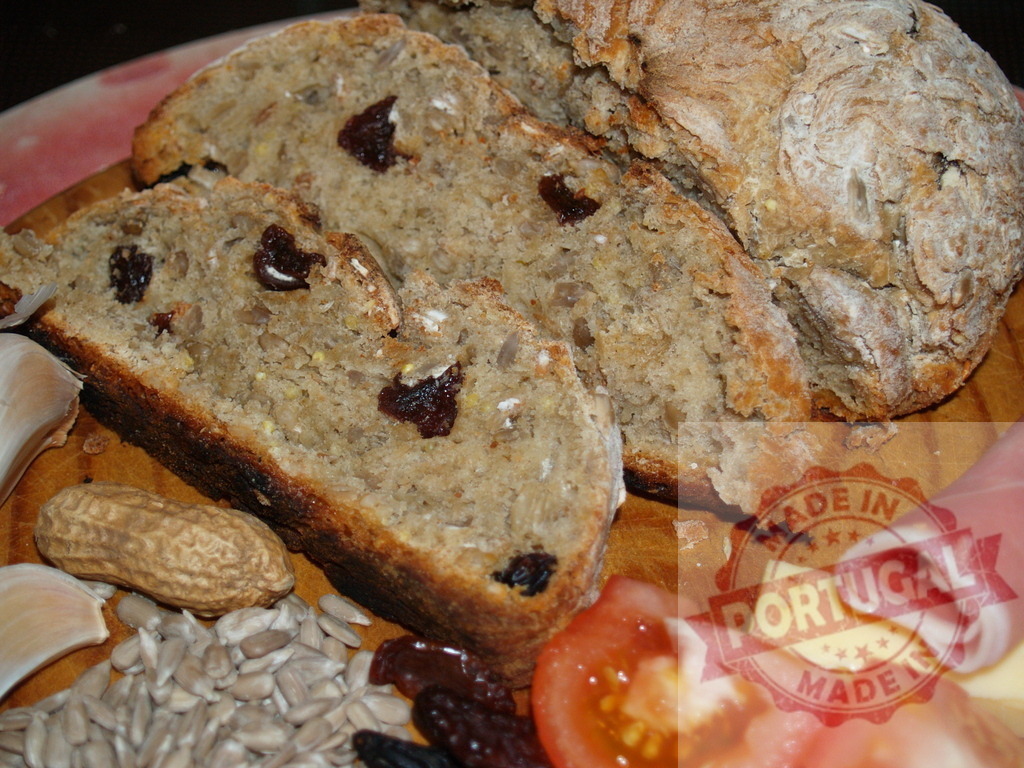 Homemade artisan bread with seeds and raisins on a rustic board | Sliced homemade bread with seeds, raisins, and charcuterie creating a rustic food platter - Realized with Pictrs.com