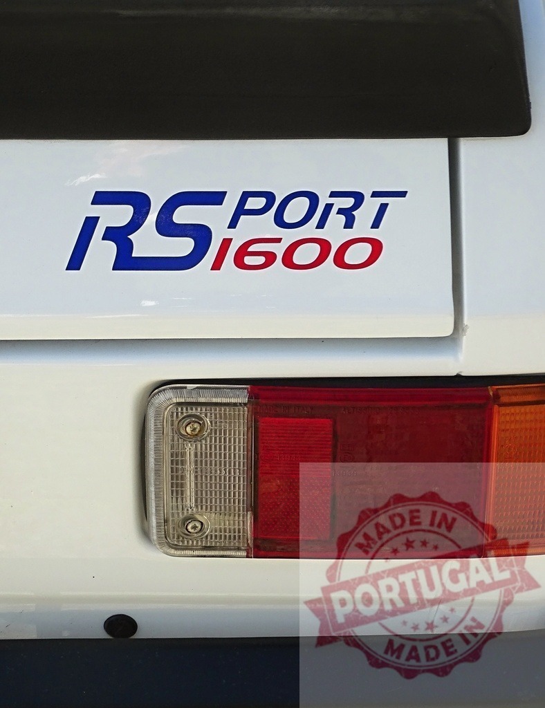 Ford Escort RS1600 Sport emblem and rear light | Ford Escort RS1600 Sport emblem details with a red taillight on white bodywork - Realisiert mit Pictrs.com