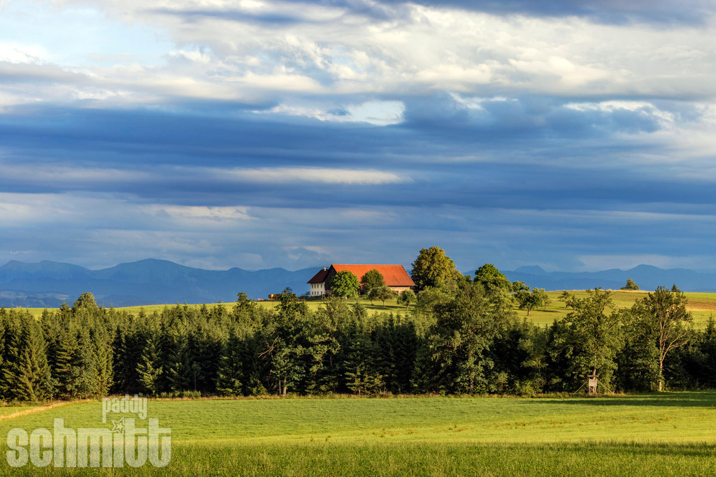 Bauernhof im Allgäu vor Bergpanorama | Ein idyllischer Bauernhof im Allgäu vor beeindruckender Bergkulisse. Die Hügel und grünen Wiesen sowie die majestätischen Berge machen den besonderen Reiz der Allgäuer Landschaft aus. - Realisiert mit Pictrs.com