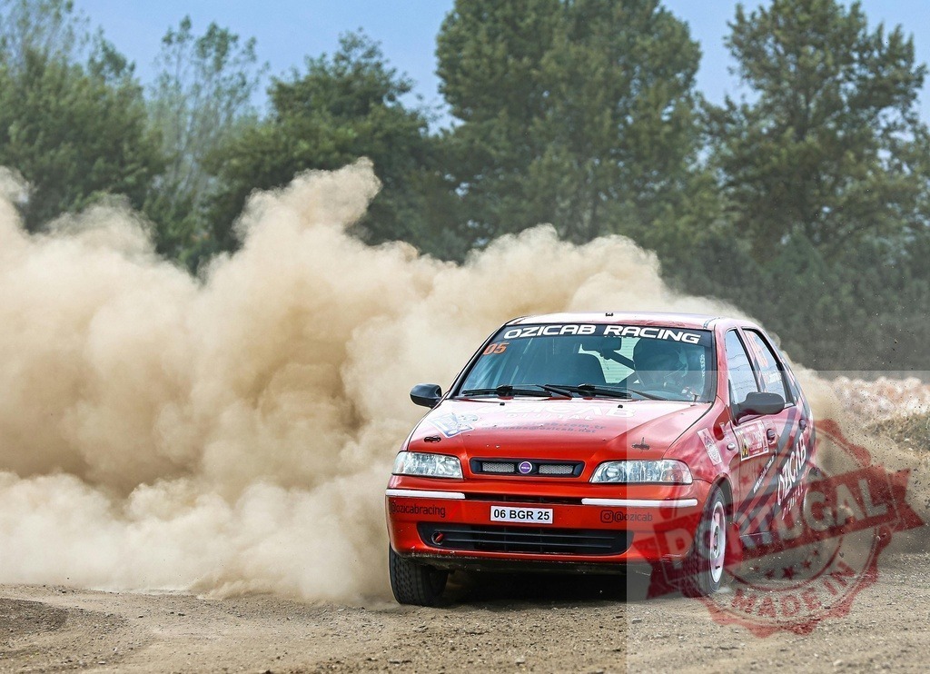 Red Fiat Palio rally car racing on dirt track creating dust | Red rally car kicking up a cloud of dust while speeding around a corner on an off-road track - Realized with Pictrs.com