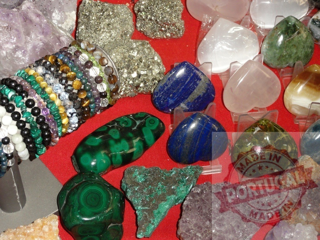 Assortment of healing crystals, gemstones, and beaded bracelets | Various natural crystals, polished gemstones, and stack of colorful beaded bracelets on display - Realized with Pictrs.com