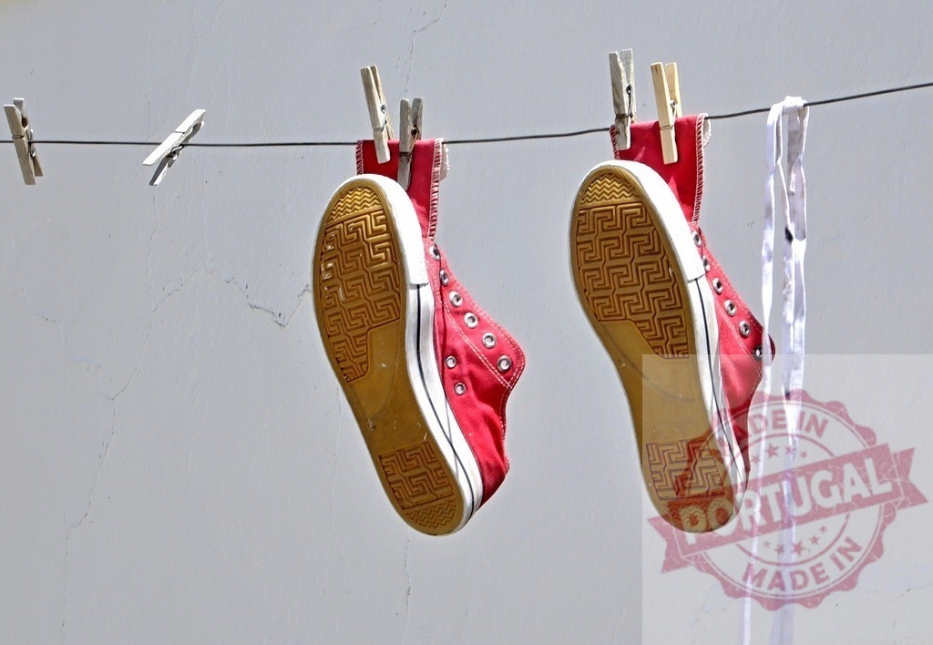 Red sneakers drying on clothesline in sunlight | Two red canvas sneakers hanging from a clothesline with clothespins - Realized with Pictrs.com