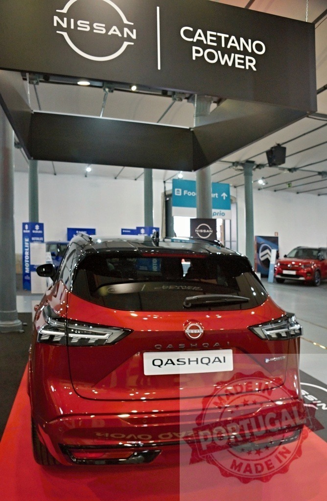 Nissan Qashqai red SUV on display at car show | Nissan Qashqai e-Power red SUV parked on a red carpet under Nissan Caetano Power sign at an automotive exhibition - Realized with Pictrs.com
