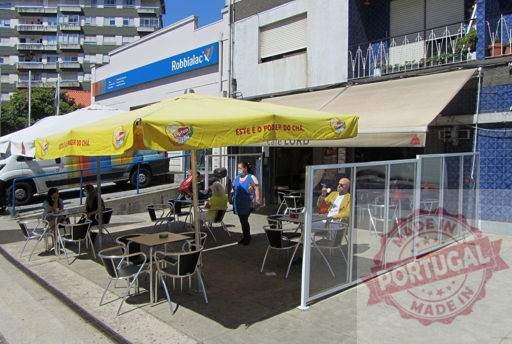 Cafe LORD outdoor seating with customers and Lipton umbrella | People enjoying outdoor seating at Cafe LORD under a Lipton umbrella on a city street - Realized with Pictrs.com