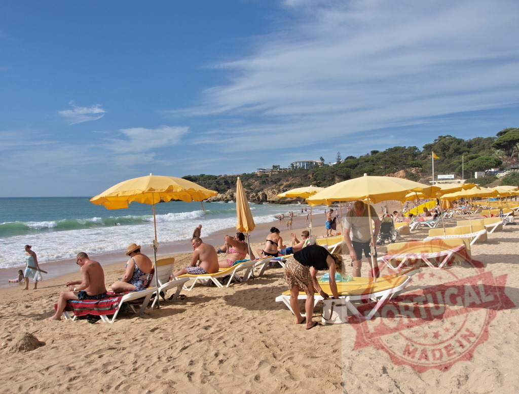 People relaxing on a sunny beach with yellow umbrellas | Tourists enjoying summer vacation and sunbathing on a sandy beach by the ocean - Realisiert mit Pictrs.com