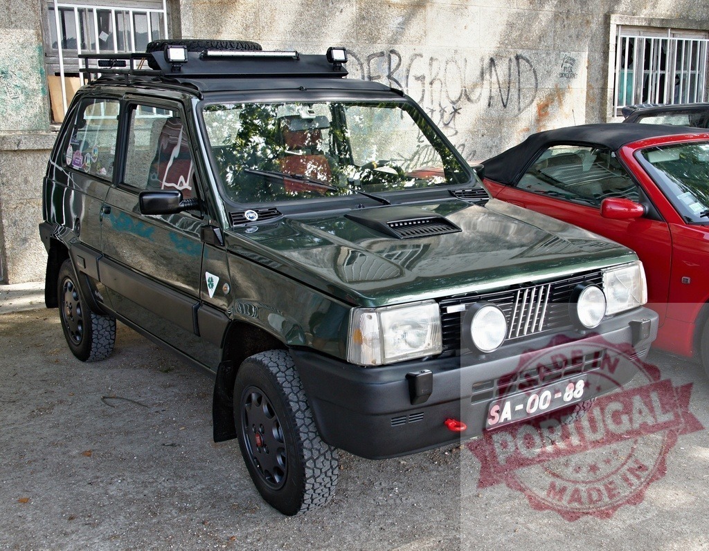 Dark green Fiat Panda 4x4 off-road classic vehicle parked | Dark green Fiat Panda 4x4 vehicle featuring rally lights and a roof rack - Realisiert mit Pictrs.com