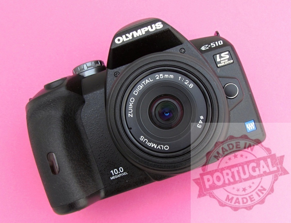 Olympus E-510 DSLR camera with Zuiko Digital lens | Black Olympus E-510 DSLR camera with a Zuiko Digital 25mm lens on a pink background - Realized with Pictrs.com