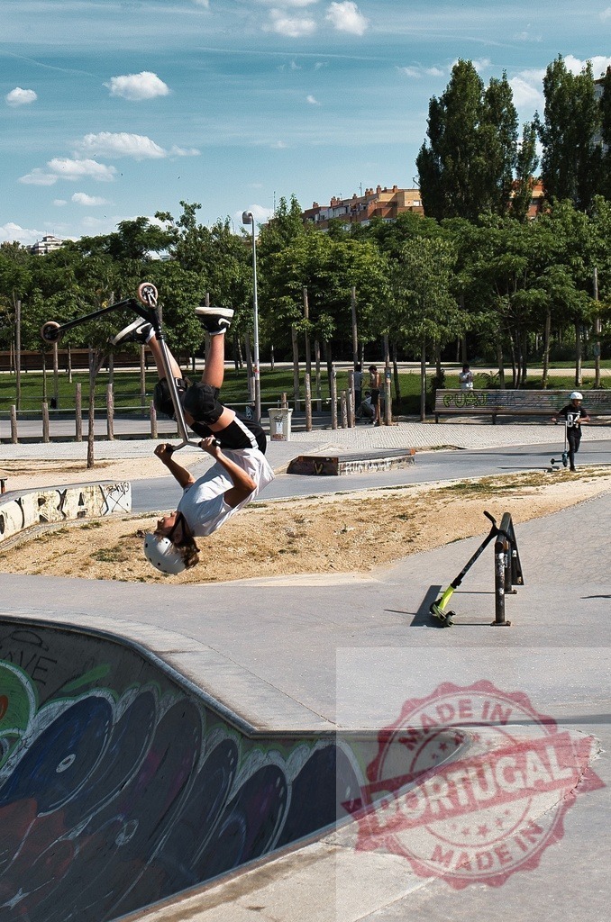 Teen performing scooter backflip trick at urban skatepark | Young rider wearing helmet executes backflip on scooter at outdoor concrete skatepark - Realized with Pictrs.com
