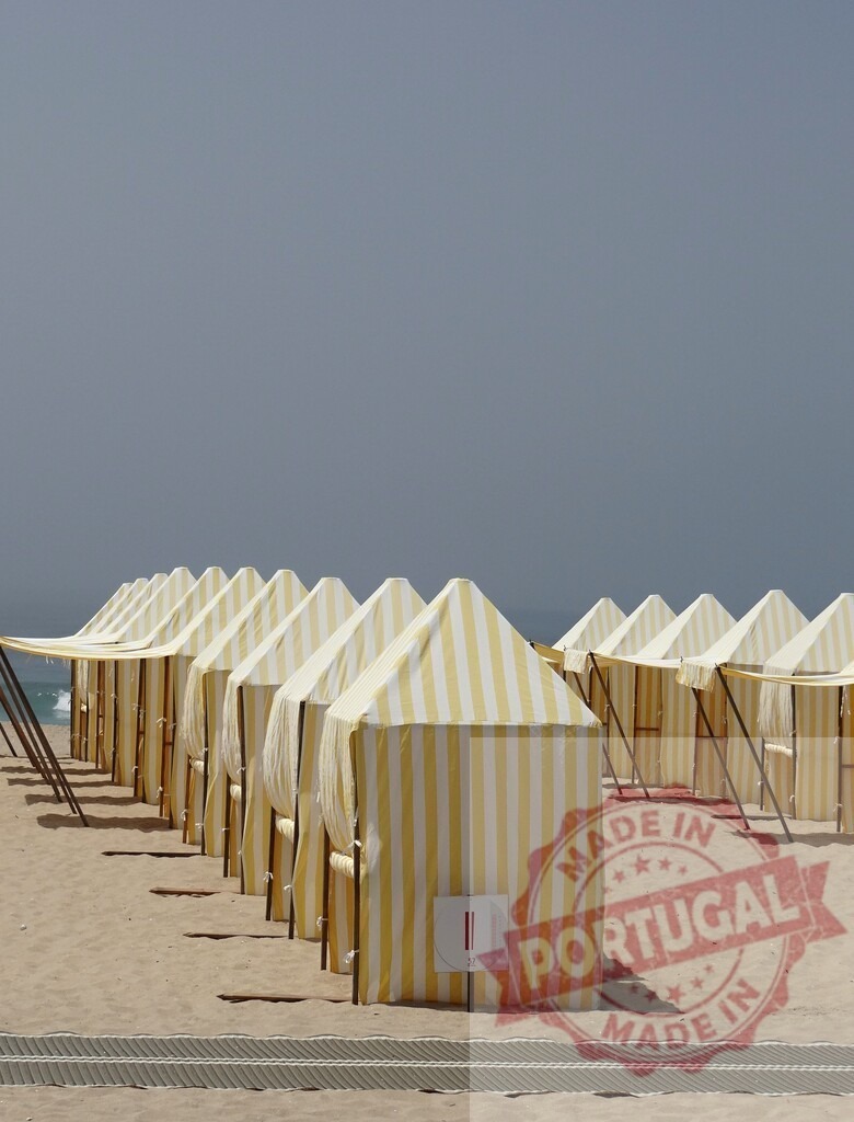 Beach tents lining a sandy ocean shore | Yellow and white striped tents standing rows on a sandy beach during summer vacation - Realized with Pictrs.com