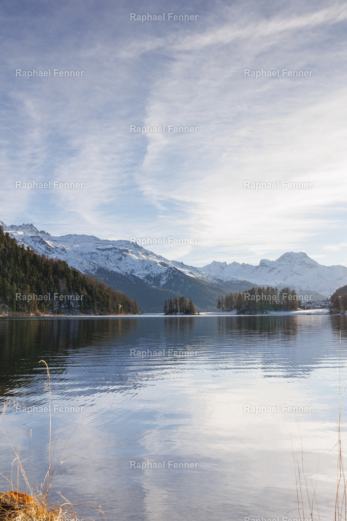 Winterstille am Lej da Champfèr | Ein klarer Winternachmittag im Engadin. Der Chapfèrersee liegt spiegelglatt zwischen verschneiten Bergen, die letzten Sonnenstrahlen tauchen die Landschaft in sanftes Licht. Dieses Bild strahlt Ruhe, Klarheit und die besondere Magie des Engadiner Winters aus – perfekt als Wandbild für alle, die alpine Weite lieben.